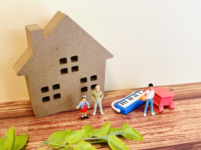 家の模型と家族のミニチュアが並ぶ住まいと暮らしのイメージ|岡山 注文住宅