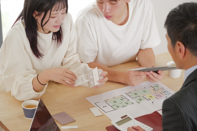 住宅会社の担当者と間取り図を見ながら注文住宅の相談をする夫婦