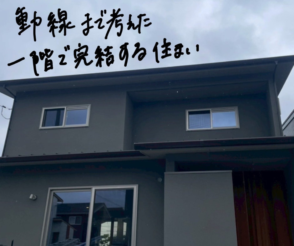 雨の日に撮影したグレーの外壁と木目の玄関まわりが印象的な2階建て住宅