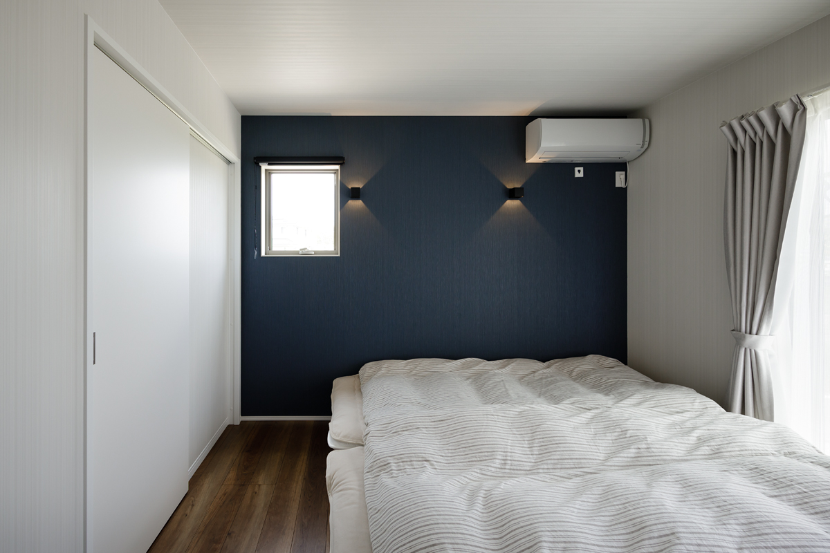 白い壁や建具に合わせた巾木とアクセントクロスのある寝室